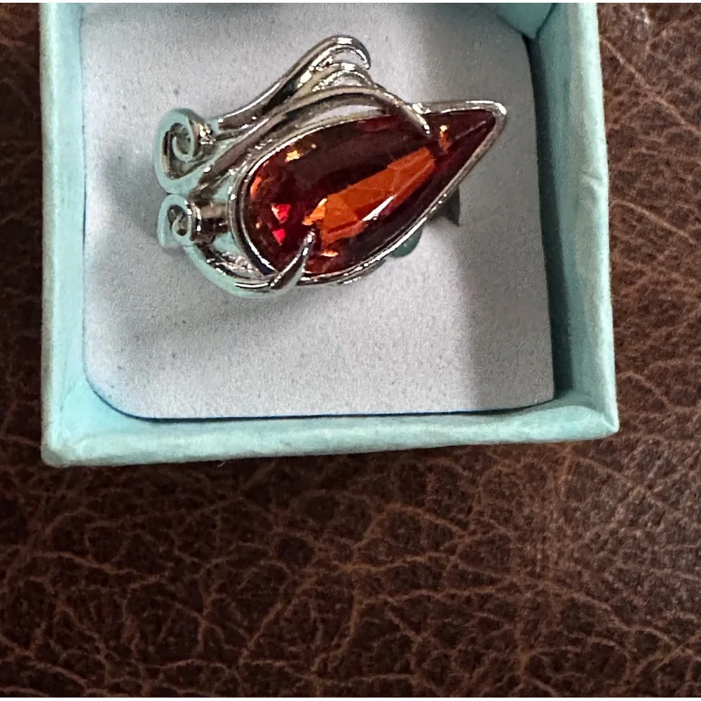 Ring in silver metal intricate with teardrop shaped amber color stone